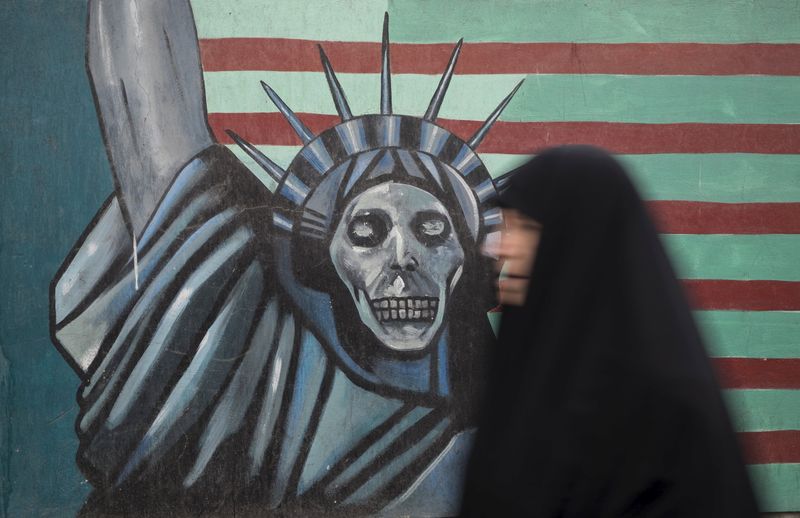 © Reuters. Iranian woman walks past an anti-U.S. mural painted on the wall of the former U.S. Embassy in Tehran