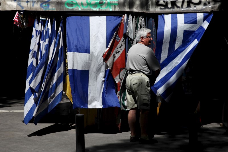 © Reuters. A man stands next to Greek national flag at a kiosk in central Athens