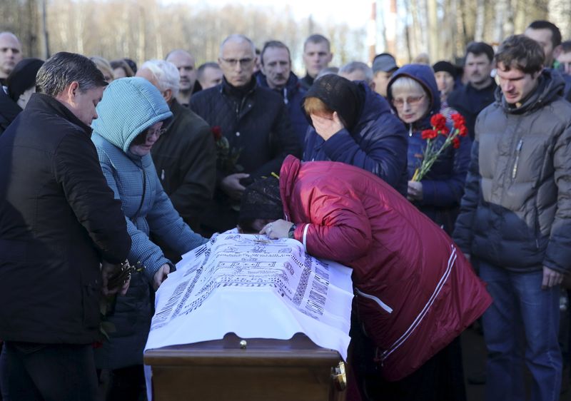 © Reuters. Relatives mourn next to coffin of victim of air crash in Egypt during funeral ceremony in St. Petersburg