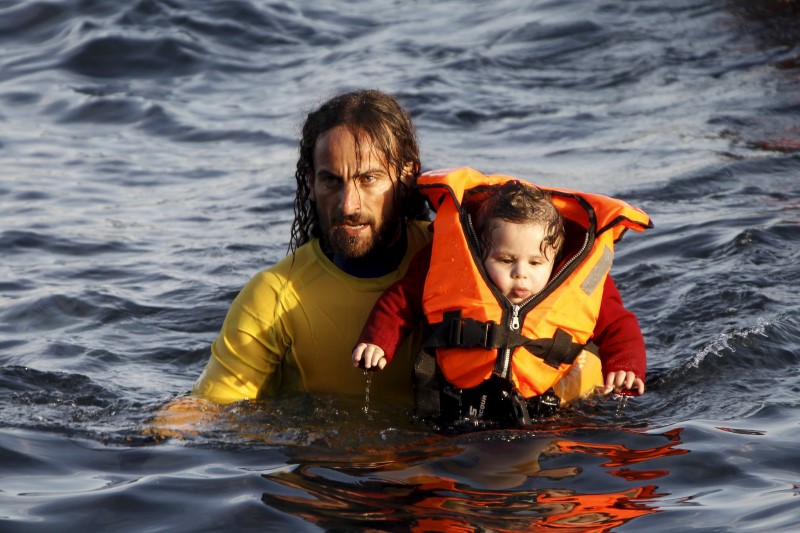 © Reuters. Homem carregando bebê resgatado no mar Egeu,  na costa da ilha grega de Lesbos