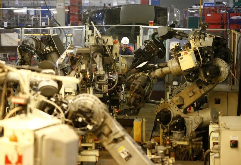 © Reuters. A worker watches robots at Futaba Industrial in Foston