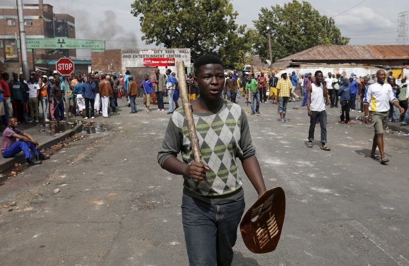 © Reuters. A local gestures as he holds a stick and a shield outside a hostel during anti-immigrant related violence in Johannesburg