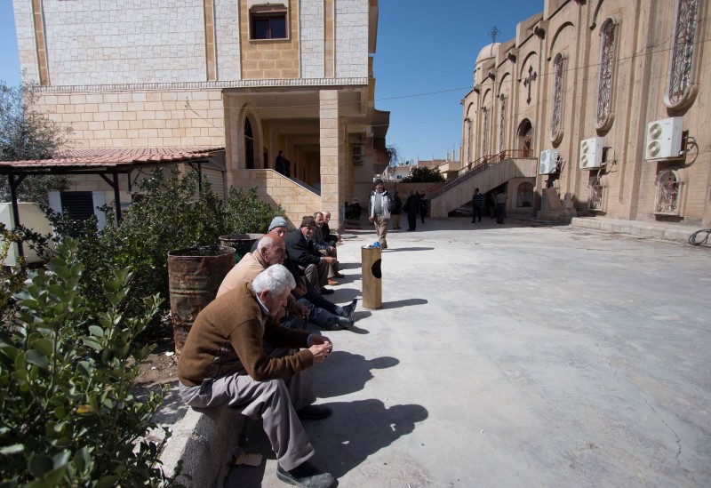 © Reuters. Displaced Assyrians, who fled from the villages around Tel Tamr, gather outside the Assyrian Church in al-Hasaka city