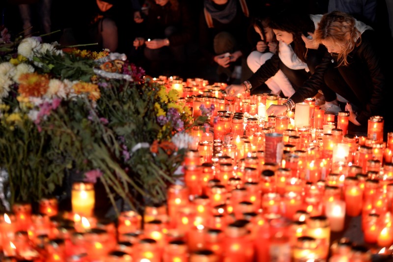 © Reuters. People light candles outside a nightclub, where a fire broke out on Friday, in Bucharest