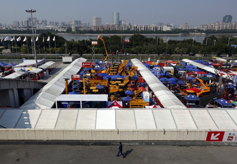 © Reuters. Man walks past construction vehicles on display at Canton Fair in the southern Chinese city of Guangzhou