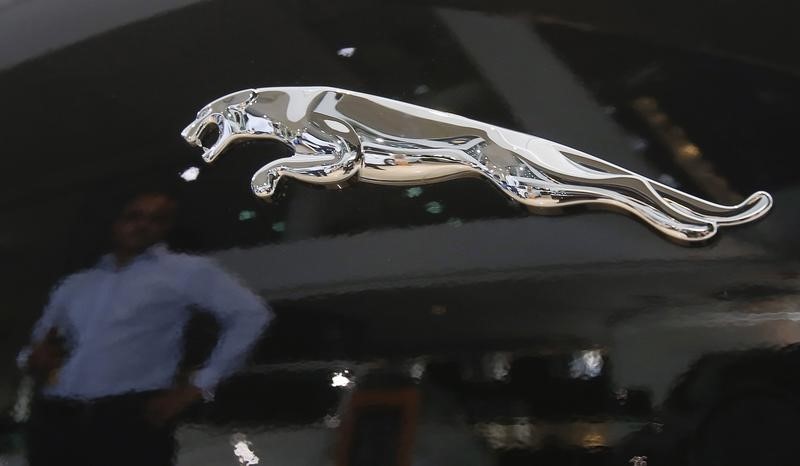 © Reuters. A man is reflected in the logo of a Jaguar vehicle at a Jaguar Land Rover showroom in Mumbai