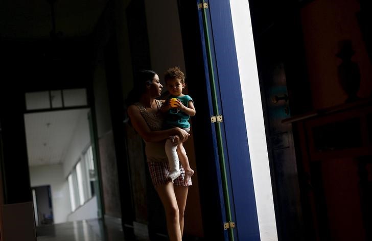 © Reuters. Professora Eliene Almeida, diretora da escola municipal de Bento Rodrigues, em pousada de Mariana com o filho no colo