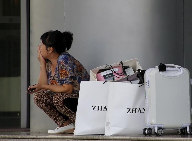 © Reuters. Una donna cinese si riposa dopo aver fatto shopping in un mall di Pechino 