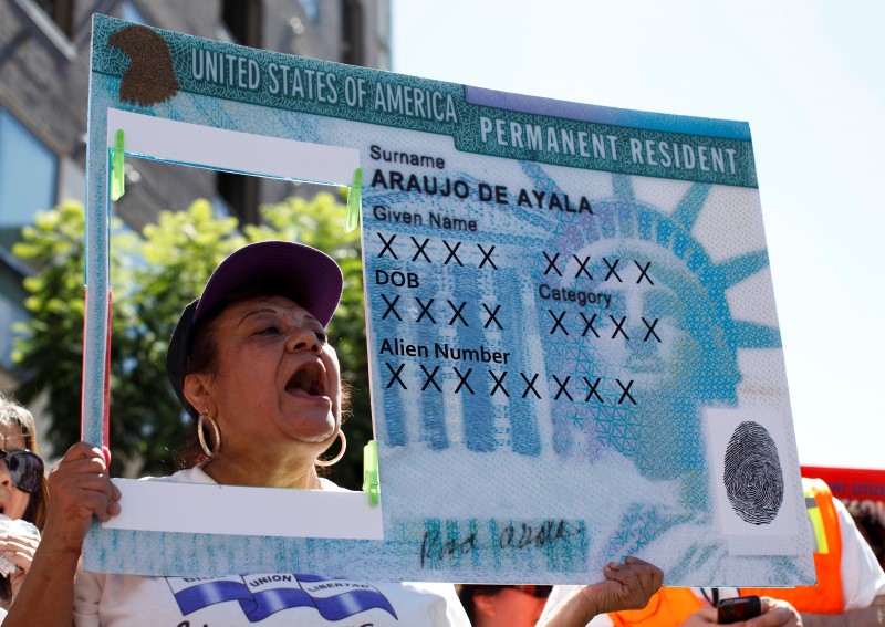 © Reuters. A woman holds a replica green card sign during a protest march to demand immigration reform in Hollywood