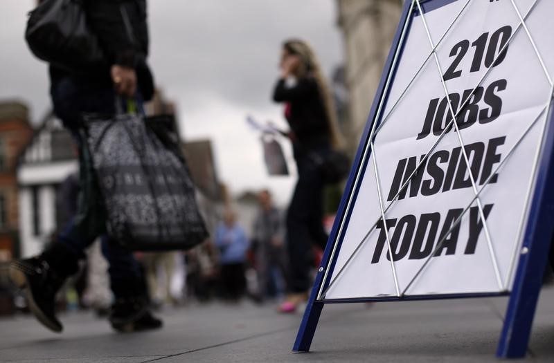 © Reuters. Shoppers walk past a newspaper advertising board promoting its job supplement in Leicester, central England