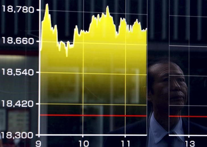 © Reuters. A pedestrian is reflected on an electronic board showing the graph of the recent fluctuations of the Japan's Nikkei average outside a brokerage in Tokyo