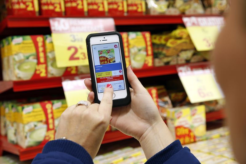 © Reuters. A woman demonstrates the use of the application "Promo C-Ou" on her smartphone at the Carrefour supermarket in Lille