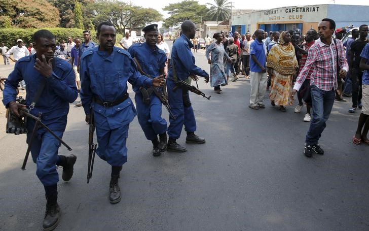 © Reuters. A protestor jeers at policemen during Presidential election day in Bujumbura's Niyakabiga district