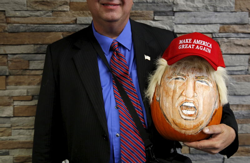 © Reuters. A supporter of U.S. Republican presidential candidate Donald Trump holds a pumpkin painted in the likeness of Trump as he waits to get into a campaign event in Springfield