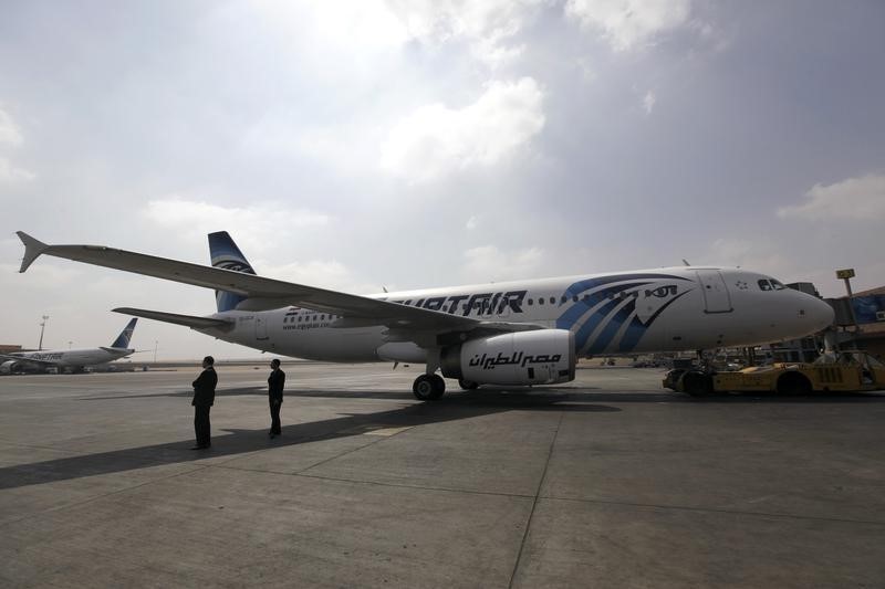 © Reuters. Airport staff stand next to an EgyptAir plane on the runway at Cairo Airport