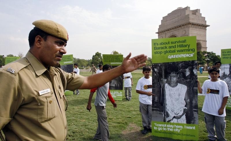 © Reuters. A policeman stops school children, brought together by Greenpeace for a climate change demonstration in New Delhi