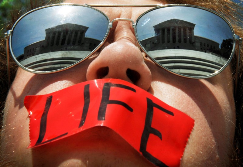 © Reuters. File photo of anti-abortion activist wearing mirrored sunglasses and a piece of tape over his mouth in front of the Supreme Court building in Washington