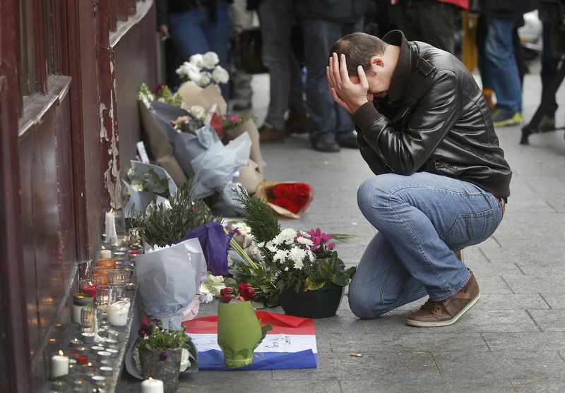 © Reuters. Un hombre brinda sus respetos a las afueras del restaurante Le Carillon en la mañana siguiente a una serie de ataques mortales en París
