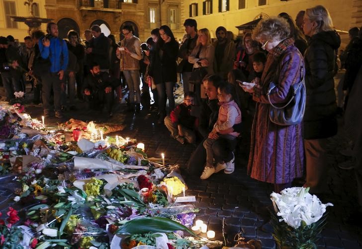 © Reuters. Varias personas encienden velas en memoría de las víctimas de los atentados en París.