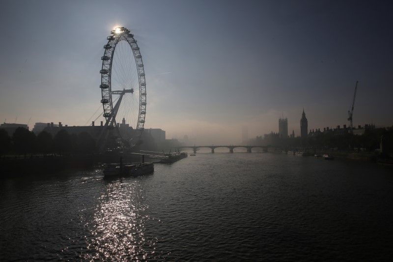 © Reuters. The sun shines through the London Eye during a foggy morning in central London