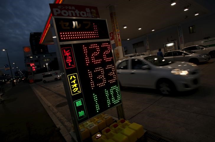 © Reuters. A car moves behind a petrol prices board after refueling at a Showa Shell Sekiyu gas station in Tokyo