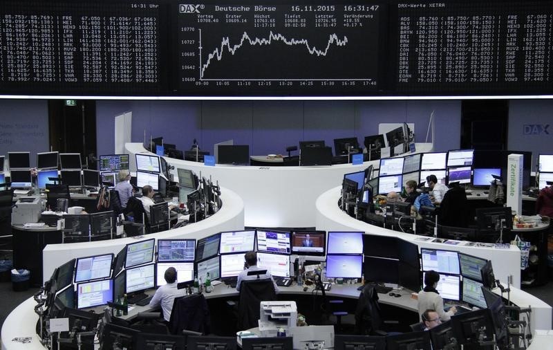 © Reuters. Traders work at their screens in front of the German share price index DAX board at the stock exchange in Frankfurt