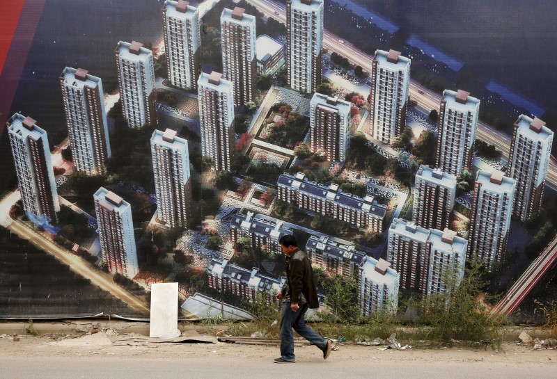 © Reuters. A man walks past a wall at a construction site for a new residential compound at the Binhai new district in Tianjin