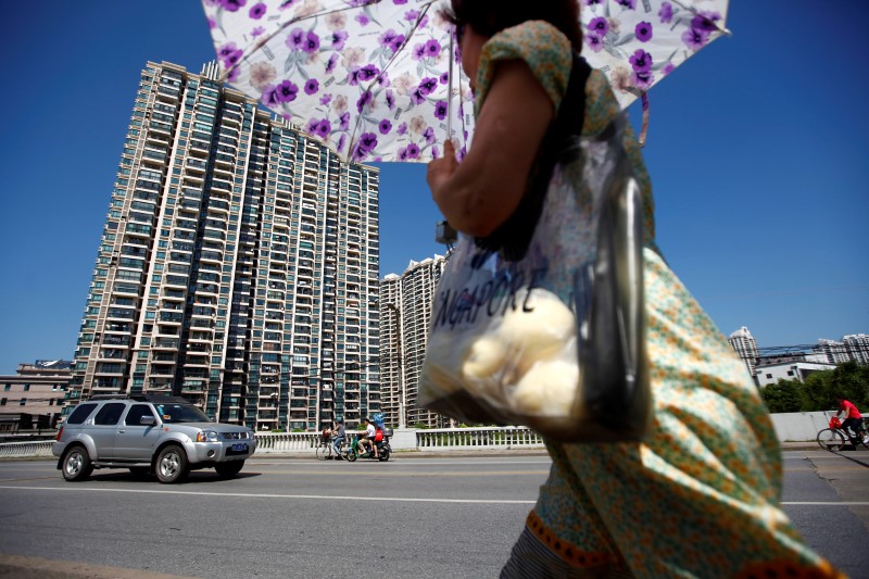 © Reuters. A woman walks past a residential site in Shanghai