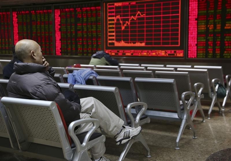 © Reuters. Investor sits in front of an electronic board showing stock information at a brokerage house in Beijing