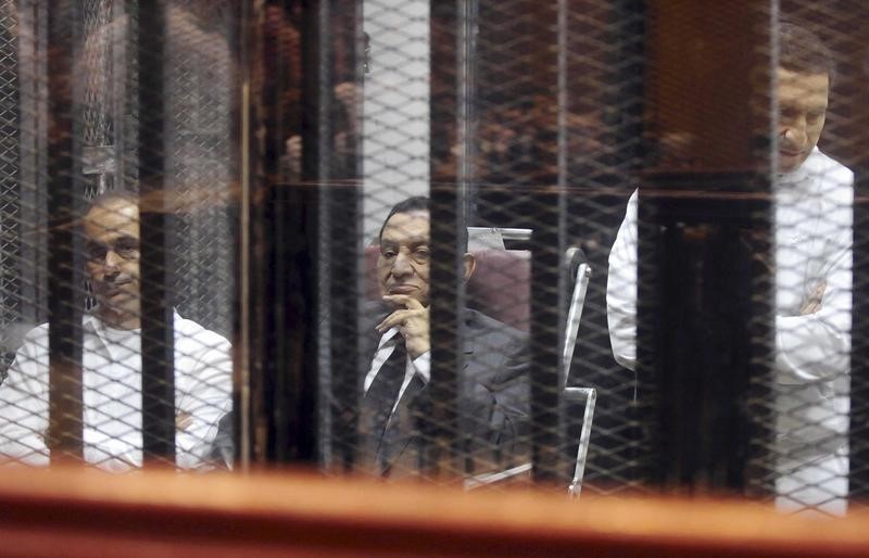 © Reuters. Egypt's ousted President Hosni Mubarak sits next to his sons Gamal and Alaa inside a dock at the police academy on the outskirts of Cairo