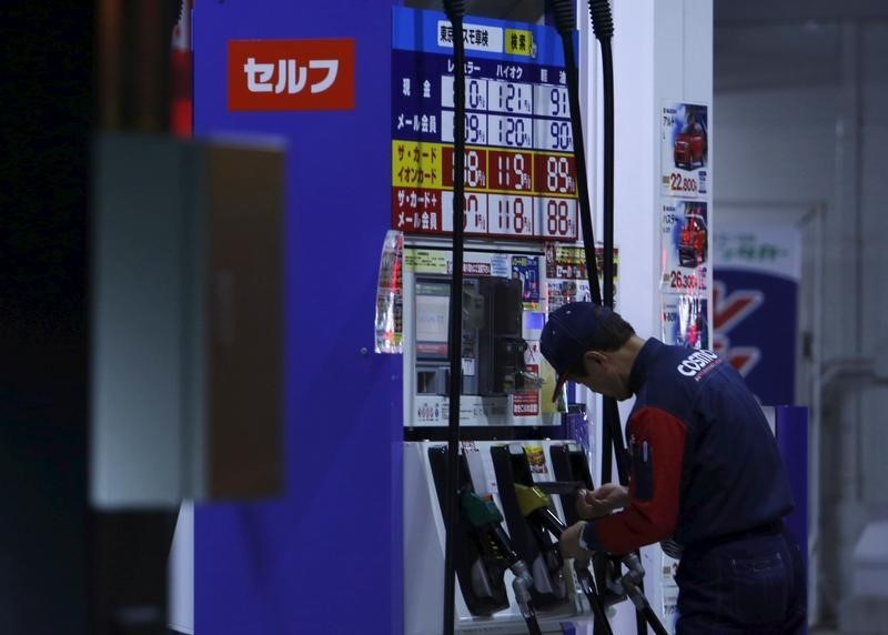 © Reuters. An employee of Cosmo Energy Holdings' Cosmo Oil service station checks its nozzles at a branch in Tokyo