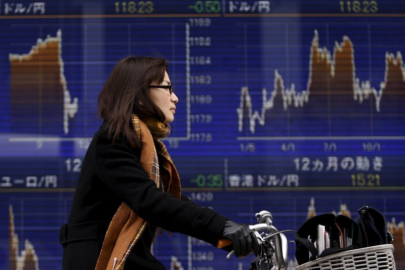 © Reuters. A woman rides on a bicycle past an electronic board showing the graph of the recent fluctuations of the exchange rates between the Japanese yen against the U.S. dollar outside a brokerage in Tokyo
