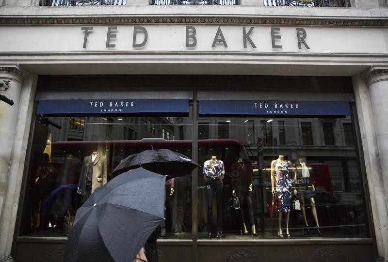 © Reuters. People shelter under umbrellas as they pass a Ted Baker a store in London, Britain