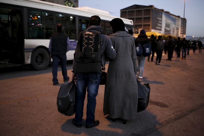 © Reuters. A Syrian refugee couple carry their belongings as refugees and migrants arrive aboard the passenger ferry Nissos Rodos at the port of Piraeus