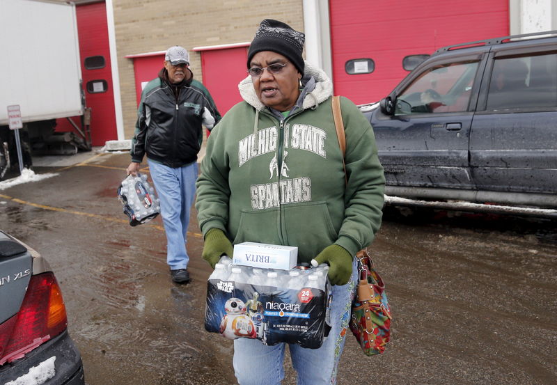 © Reuters. Flint resident Ruby Adolph carries bottled water and a replacement water filter she received at a fire station in Flint, Michigan