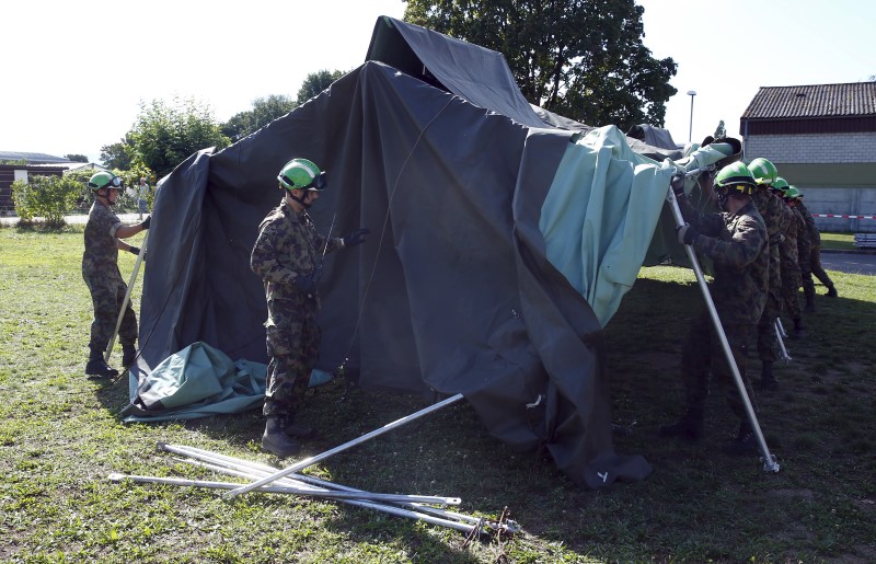 © Reuters. Swiss Army personnel build a tent outside a refugee camp in Lyss