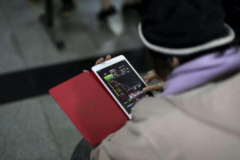 © Reuters. An investor checks stock information on a mobile device at a brokerage house in Shanghai