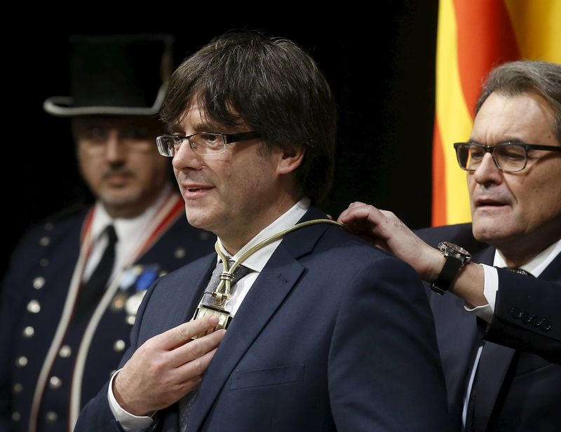 © Reuters. New Catalan President Puigdemont receives a medal from outgoing Catalan President Mas during Puigdemont's swearing-in ceremony as President of the Generalitat de Catalunya at Palau de la Generalitat in Barcelona