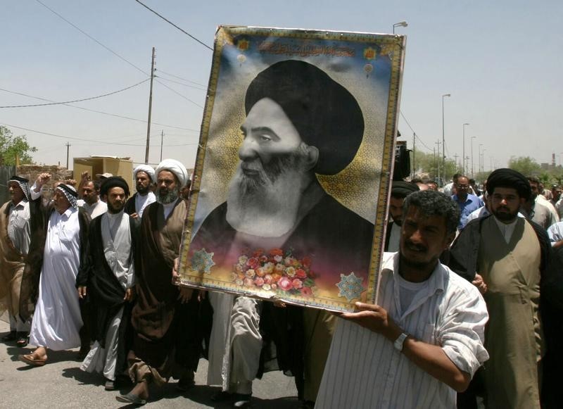 © Reuters. Iraqis carry a poster of top Shi'ite cleric Grand Ayatollah Ali al-Sistani during a demonstration in Najaf