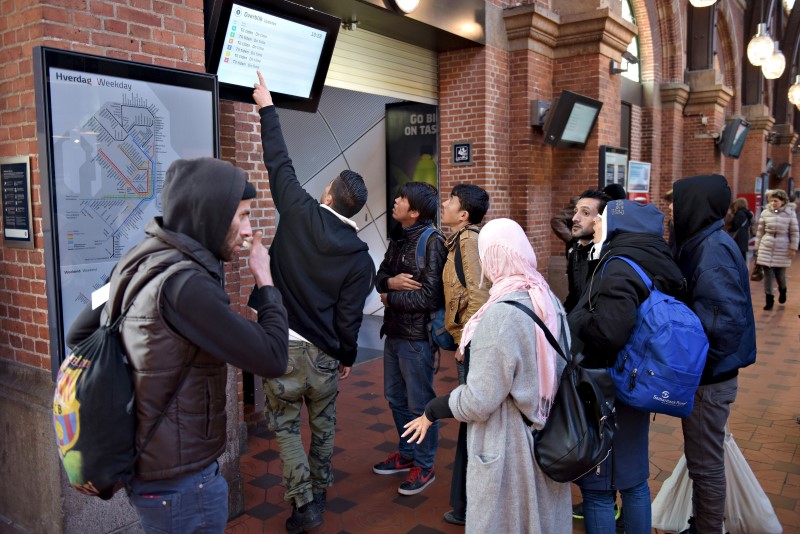 © Reuters. A group of migrants check a departure board at Copenhagen Central Station