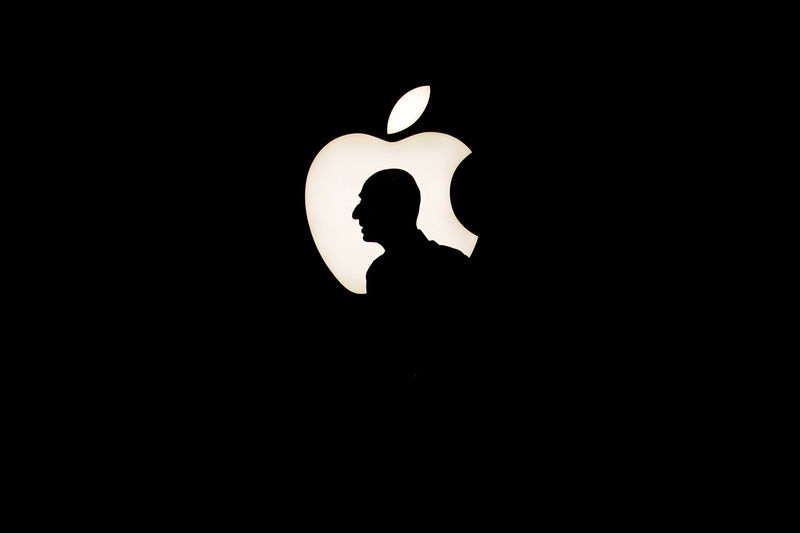 © Reuters. File photo of a man walking past a backlit Apple logo during an Apple media event in San Francisco
