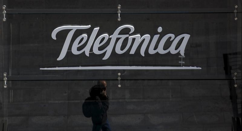 © Reuters. A reflection of a man talking on his phone is seen outside Telefonica's flagship store in central Madrid