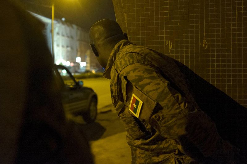 © Reuters. A Burkinabe soldier looks out from behind a wall before A counter-assault on Islamist gunmen at the Splendid Hotel in Ouagadougou