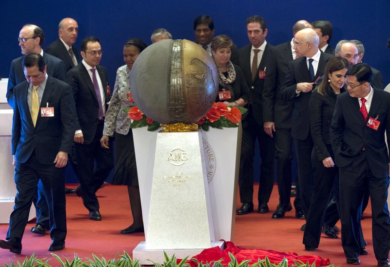 © Reuters. Representatives of the founding nations of the Asian Infrastructure Investment Bank (AIIB) walk around a sculpture after it was unveiled during the opening ceremony of the AIIB in Beijing