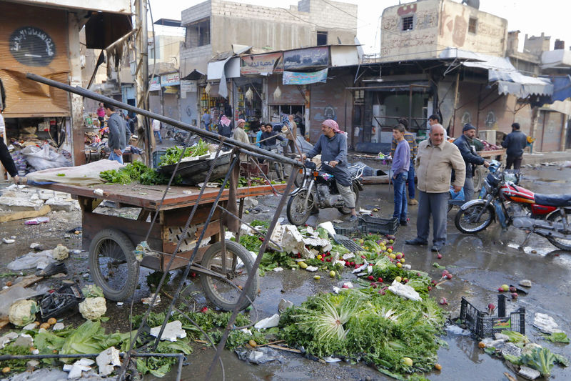 © Reuters. People inspect a site after hit by what activists said were air strikes by forces loyal to Syria's President Bashar al-Assad in Raqqa, eastern Syria, which is controlled by the Islamic State