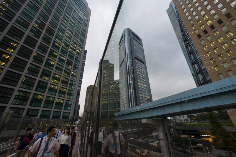 © Reuters. People walk in shadows of office skyscrapers in business district in Tokyo