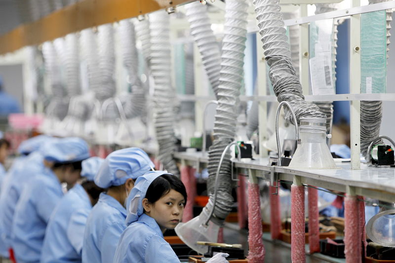 © Reuters. File photo of an employee looking up while working along a production line in Suzhou Etron Electronics Co. Ltd's factory in Suzhou