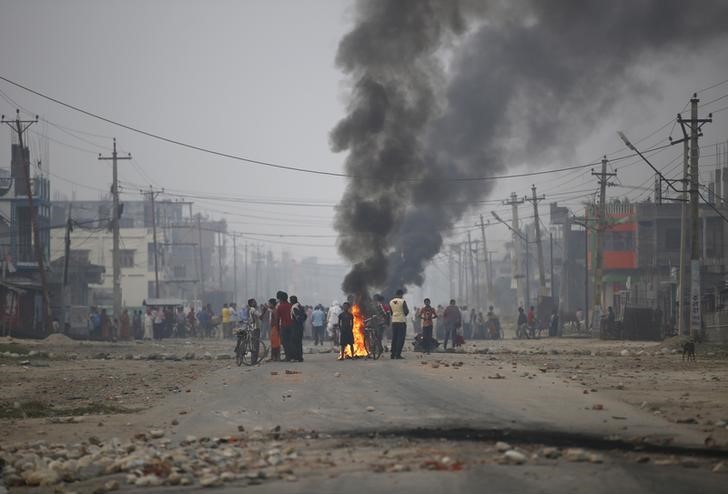 © Reuters. Protesters stand near burning tyres as they gather to block highway connecting Nepal and India, during general strike called by Madhesi protesters demonstrating against new constitution in Birgunj 