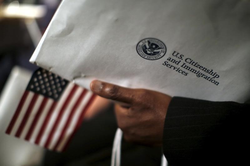 © Reuters. A man holds an envelope from the U.S. Citizenship and Immigrations Service during a naturalization ceremony at the National Archives Museum in Washington