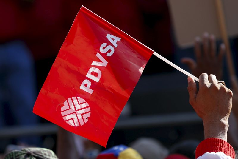 © Reuters. A worker of the Venezuelan state oil company PDVSA holds a flag with the company logo, during a meeting with Venezuela's President Nicolas Maduro outside Miraflores Palace in Caracas